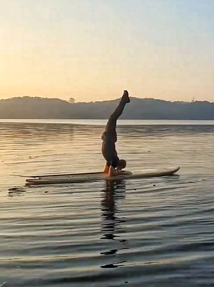 Caio Naddeo em postura invertida de SUPYOGA no stand up paddle